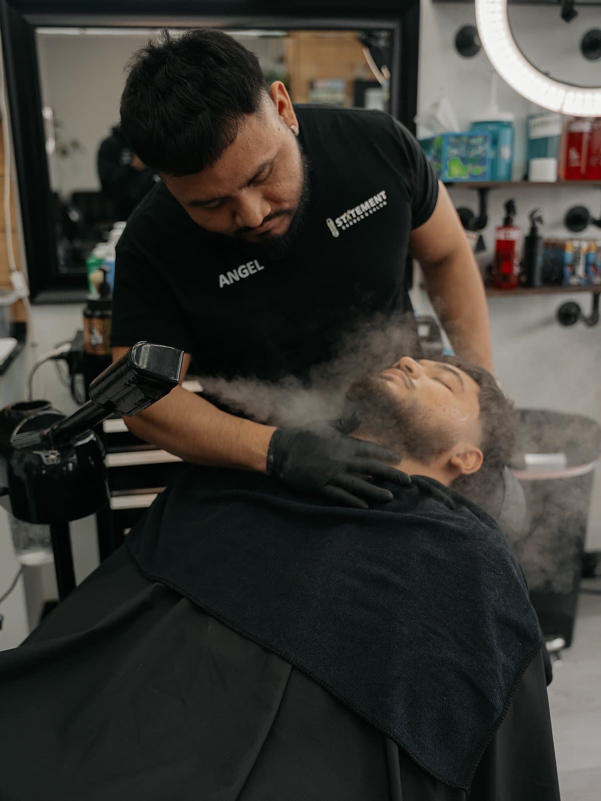 Angel Bolanos dando un tratamiento de barba con vapor y toalla caliente en Statement Barbershop & Salon, Kennewick