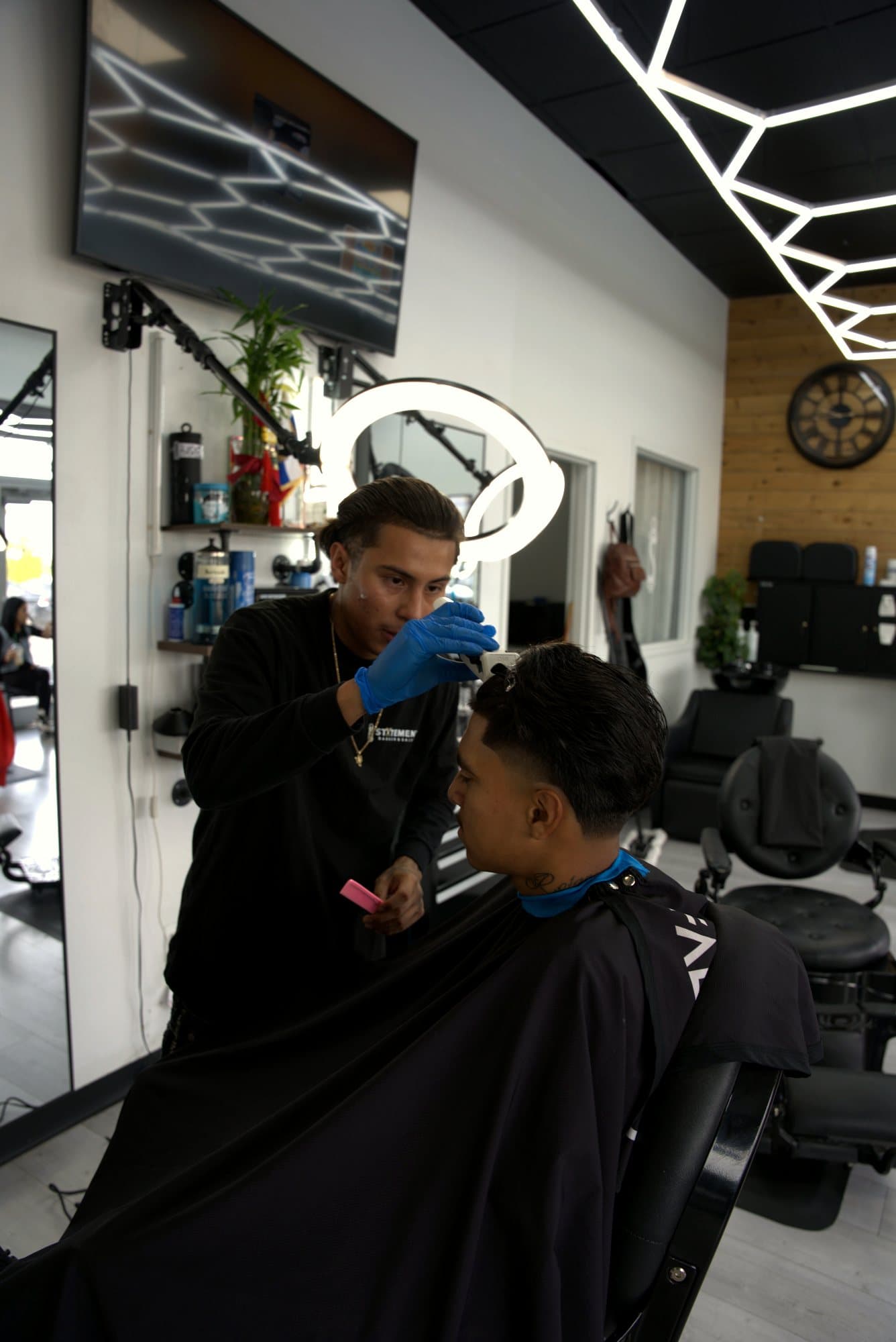 Carlos Cortez cutting a client's hair under a ring light at Statement in Kennewick
