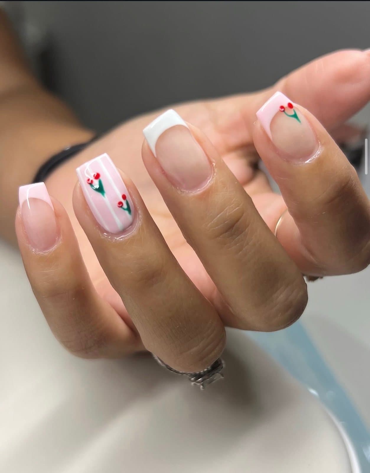 Uñas con punta francesa y flores pintadas a mano de Statement Barbershop & Salon