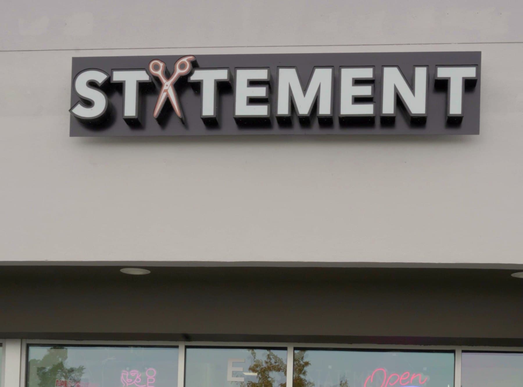 Letrero de Statement Barber & Salon sobre las ventanas del local en W Canal Dr, Kennewick, WA
